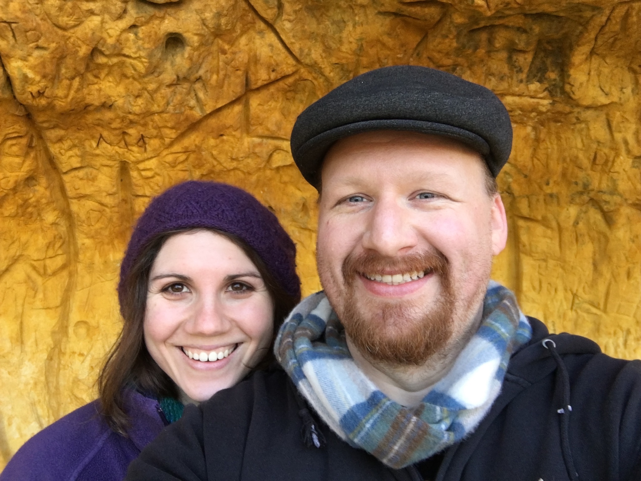 Ioana and Eric making playful faces together in front of a brightly carved golden wall